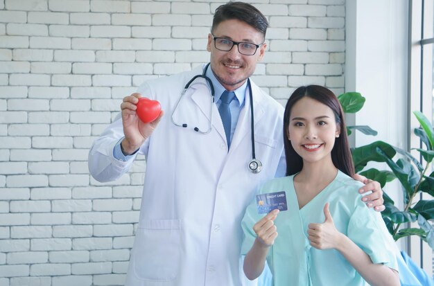 Foto ritratto di un medico in forma di cuore mentre un paziente tiene in mano una carta di credito in clinica