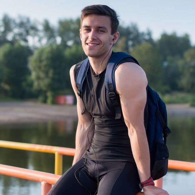 Фото Портрет спортивного человека, сидящего на пирсе возле пруда