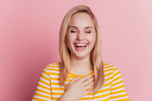 Фото Портрет смешной веселой блондинки руки грудь смеяться на розовом фоне