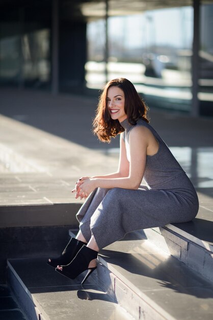 Фото Портрет улыбающейся молодой женщины, сидящей на ступеньках