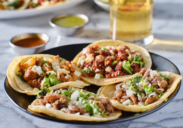 Photo platter of mexican street tacos with carne asada, chorizo, and al pastor in corn tortillas