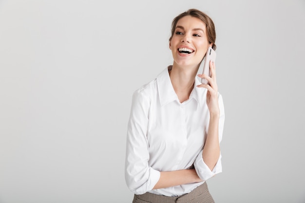 pleased beautiful woman laughing and talking on mobile phone isolated over white background