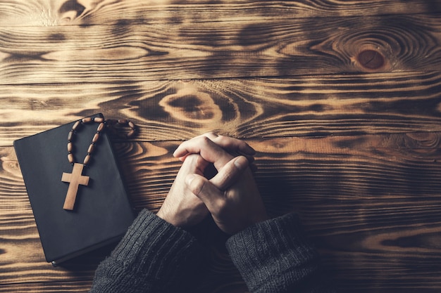 Фото Молитва руки человека крест на библии на деревянном столе