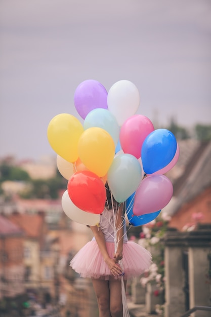 Фото Красивая девушка с большими красочными латексными воздушными шарами позирует на улице старого города