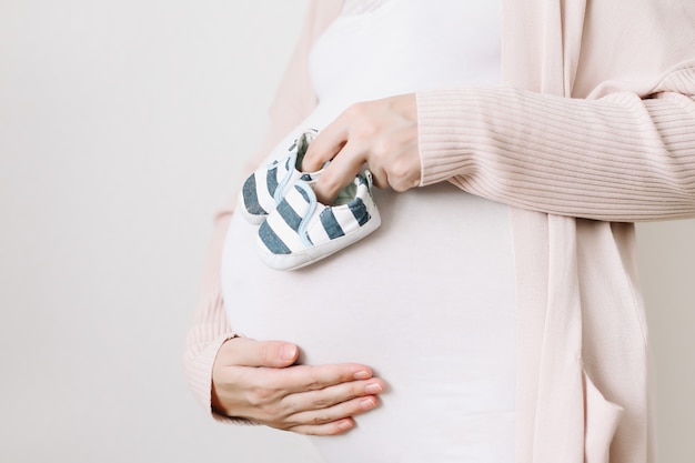 беременная женщина держит обувь для новорожденного
