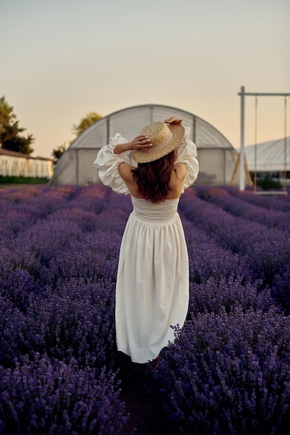 Беременная девушка в шляпе в сиреневом поле на закате