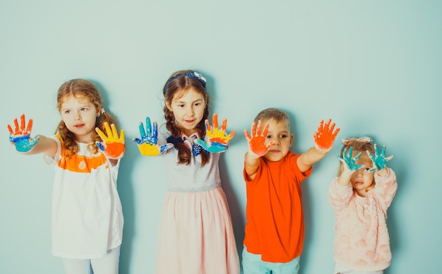 Фото Дети дошкольного возраста, стоящие в ряд, показывают на камеру свои нарисованные разноцветные руки. творческое проведение времени в детском саду с детьми разного возраста
