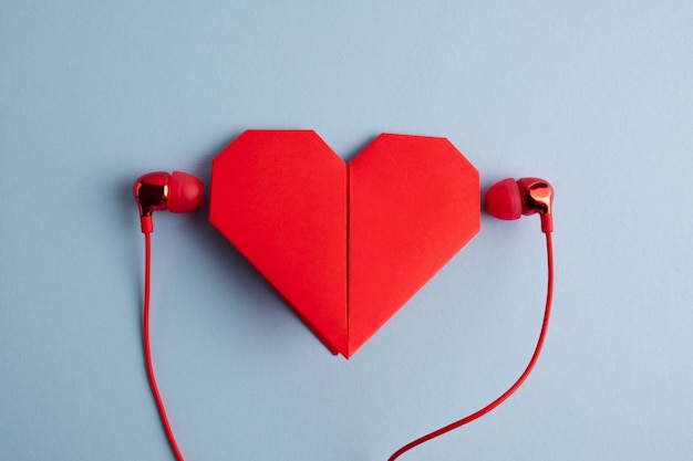 Photo red origami heart with headphones on blue table