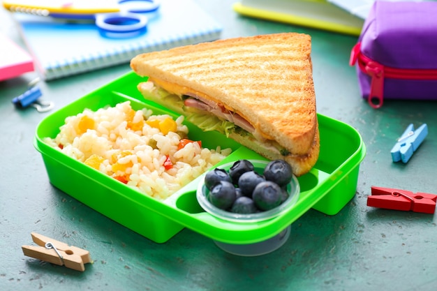 School lunchbox met lekker eten en briefpapier op tafel