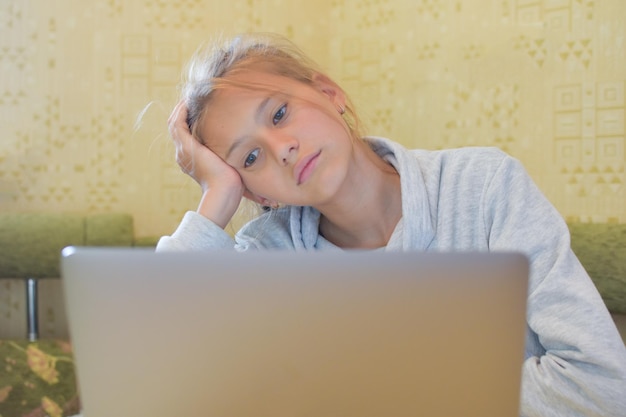 退屈な宿題をコンピュータオンライン学習距離で宿題をしている女子高生
