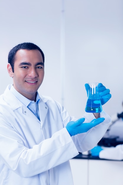 Студент науки, держащий синий химикат в стакане