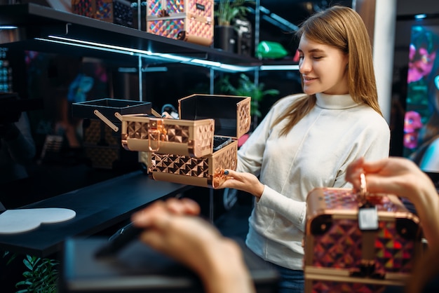 Фото Консультант-продавец помогает женщине с выбором футляра для косметики в магазине макияжа. покупательница в магазине красоты