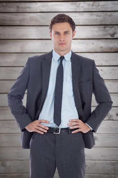 Photo serious businessman with hands on hips against wooden planks