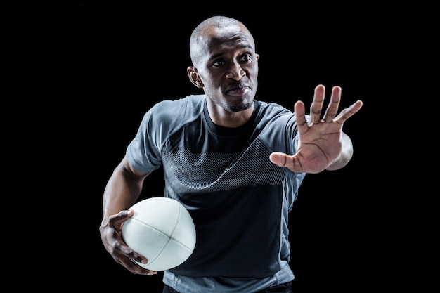 Серьезный спортсмен gesturing, держа мяч для регби