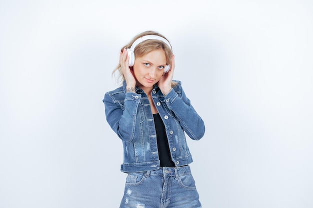 Seriously girl with headphone is looking at camera by holding headphone on white background