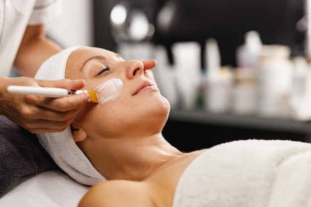 Photo shot of a beautiful mature woman getting a facial mask treatment at the beauty salon.