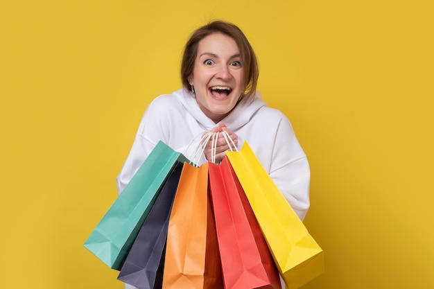 Photo shopping woman smiling holding colored shopping bags isolated on yellow background studio shot