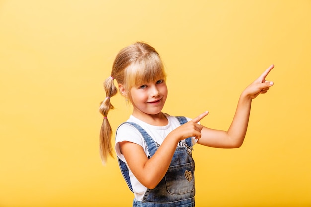 Фото Боковой портрет маленькой девочки. она милая милая привлекательная веселая блондинка указывая пальцем