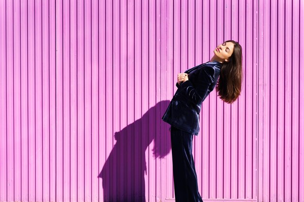 Фото Боковой вид женщины, стоящей на розовой стене