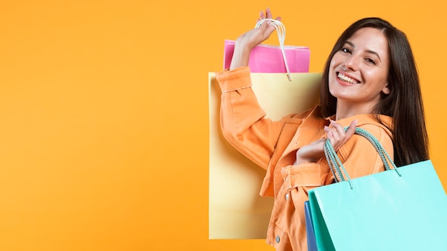 Side view of smiley woman holding up shopping bags