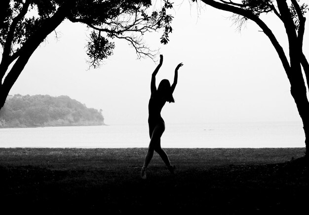 Фото Силуэт женщины танцует на поле на фоне моря