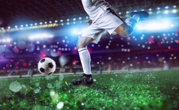 Футболист готов ударить футбольный мяч на стадионе во время матча.