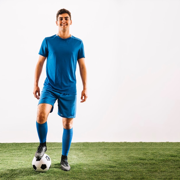 Smiling sportsman stepping on ball