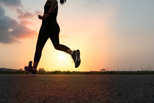 Foto donna sportiva in esecuzione su una strada. addestramento della donna di forma fisica al tramonto