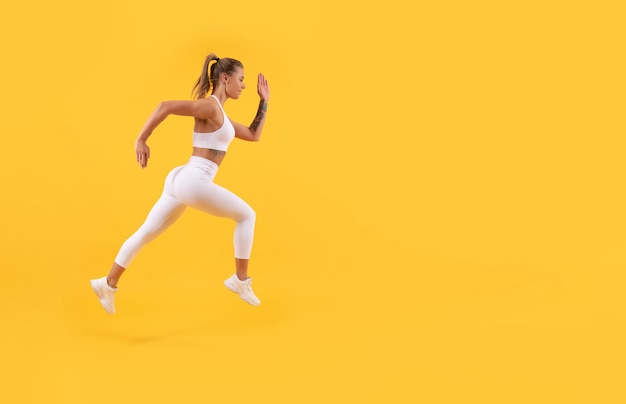Спортивная бегунья бегает с копировальным пространством на желтом фоне