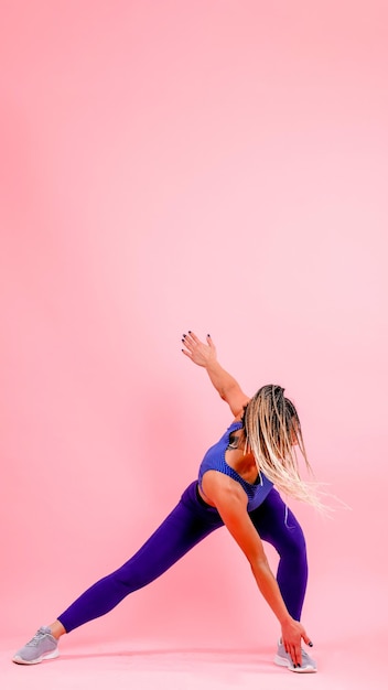 Фото Спортивная девушка делает упражнения на розовом фоне