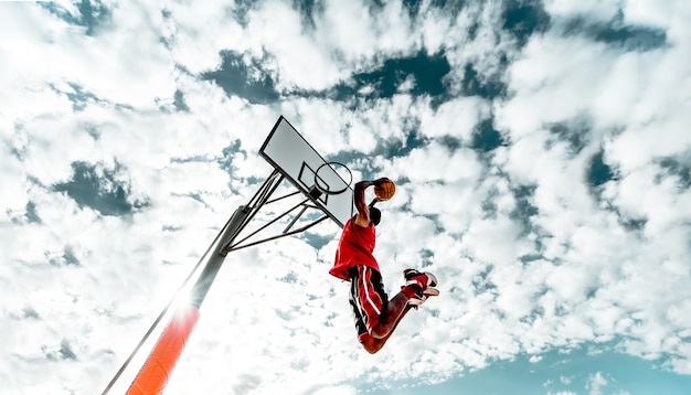 Photo street basketball player making a powerful slam dunk on the court  athletic male training outdoor