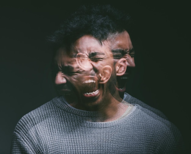Photo studio shot of a young man experiencing mental anguish and screaming against a black background