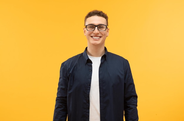 Photo stylish young guy wearing eyeglasses posing isolated on yellow background