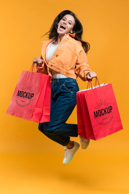 Young woman jumping and holding shopping bags mock-up