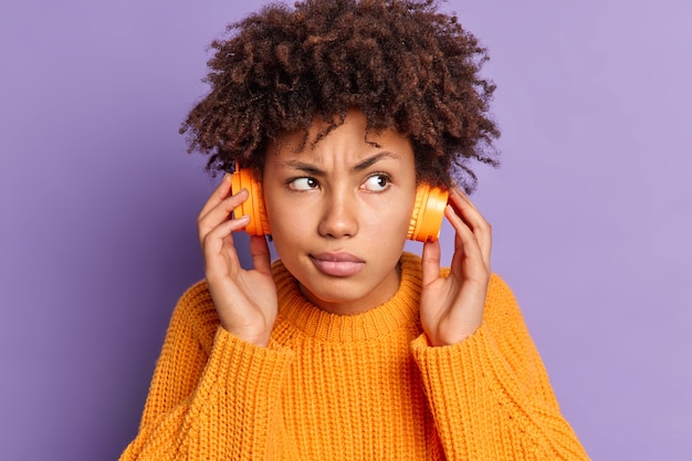 Gratis foto close-up portret van ernstige jonge african american vrouw luistert audio track geconcentreerd ergens draagt draadloze koptelefoon poses