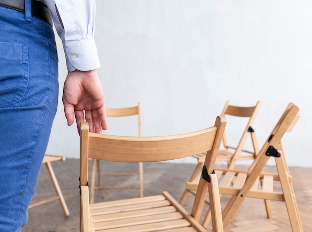 Gratis foto achteraanzicht van persoon met lege stoelen voorbereid op groepstherapie