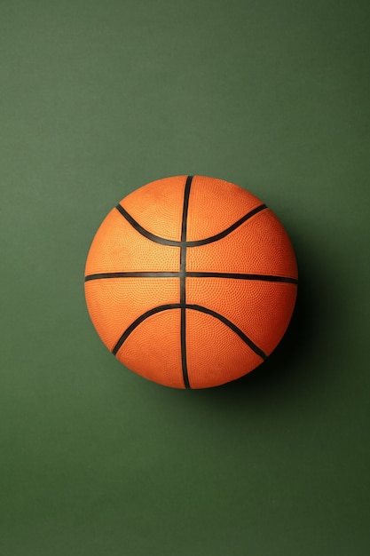Gratis foto fel oranje-bruine basketbalbal. professionele sportuitrusting geïsoleerd op groene studio achtergrond. concept van sport, activiteit, beweging, gezonde levensstijl, welzijn. moderne kleuren.