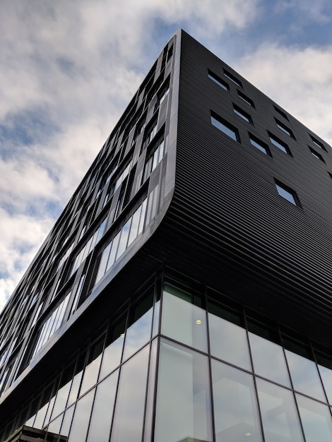 Gratis foto verticale lage hoek shot van een hoogbouw zwart gebouw met glazen ramen