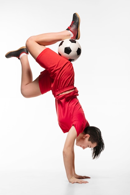 Gratis foto vrouw doet acrobatiek met voetbalbal