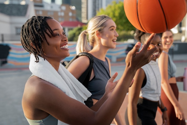 Gratis foto zijaanzicht vrouwelijke vrienden die basketbal spelen