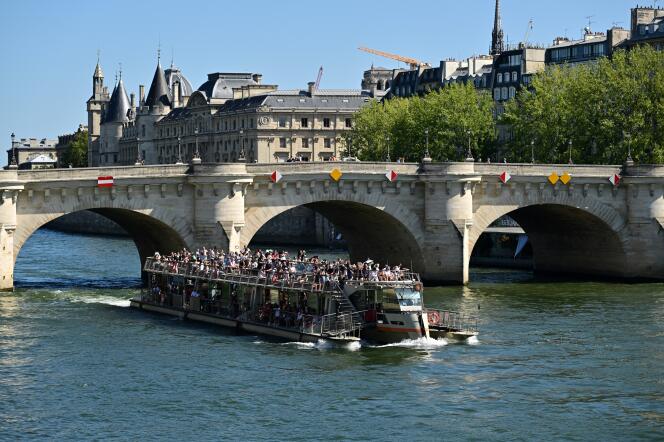 Des touristes lors d’une balade en bateau sur la Seine, au passage du Pont-Neuf, à Paris, le 21 août 2023.