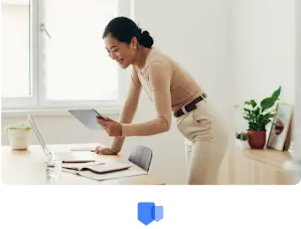 一位女士俯身在办公桌前，用平板电脑查看自己的荣誉和奖励。