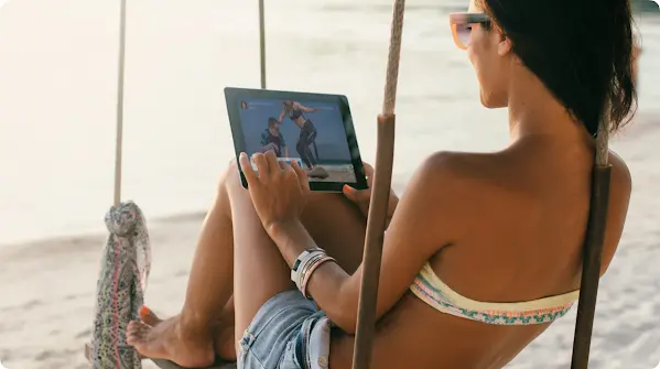 Μια γυναίκα κοιτάζει ένα tablet σε μια παραλία
