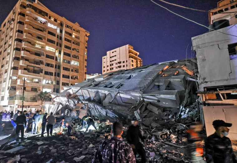 People gather at the site of a collapsed building in the aftermath of Israeli air strikes on Gaza City on May 11, 2021.