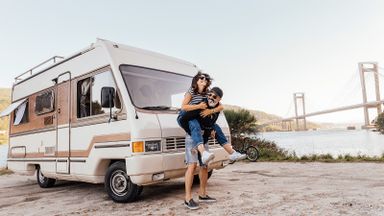 man giving woman a piggyback in front of an RV
