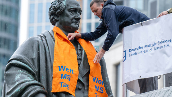 Fußballgott trifft auf Dichterfürst: Der ehemalige Eintracht-Spieler Alex Meier legt dem Goethedenkmal zu Beginn der Aktionswoche „Denk-mal-an-MS“ einen orangefarbenen Schal um.