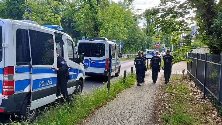 Polizisten gehen am abgesperrten Tatort in der Potsdamer Geschwister-Scholl-Straße entlang.
