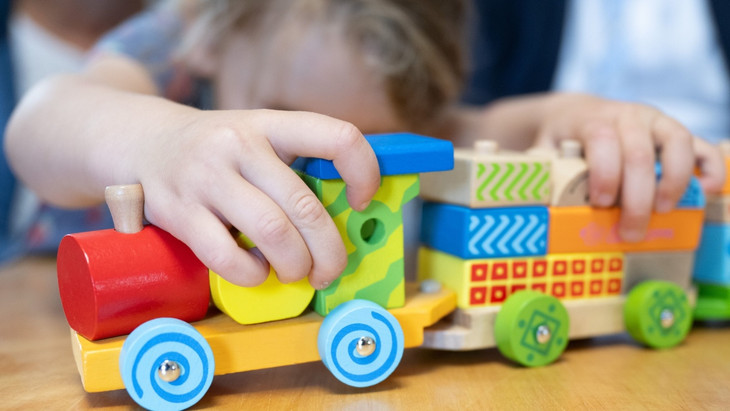 Ein Kind spielt mit einem Zug in einer Kindertagesstätte.