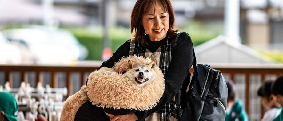 Gehören zusammen: Atsuko Sato trägt die alte Hundedame.