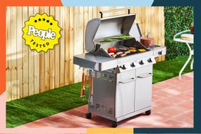 The Monument Grills 4-Burner Propane Gas Grill on a patio in a fenced yard